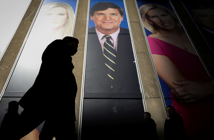 People pass by a promo of Fox News host Tucker Carlson on the News Corporation building in New York, U.S., March 13, 2019 (credit: REUTERS/BRENDAN MCDERMID)