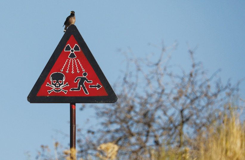 A BIRD SITS on a radiation sign at the uranium ore dump near the town of Mailuu-Suu, Kyrgyzstan. (credit: PAVEL MIKHEYEV/REUTERS)