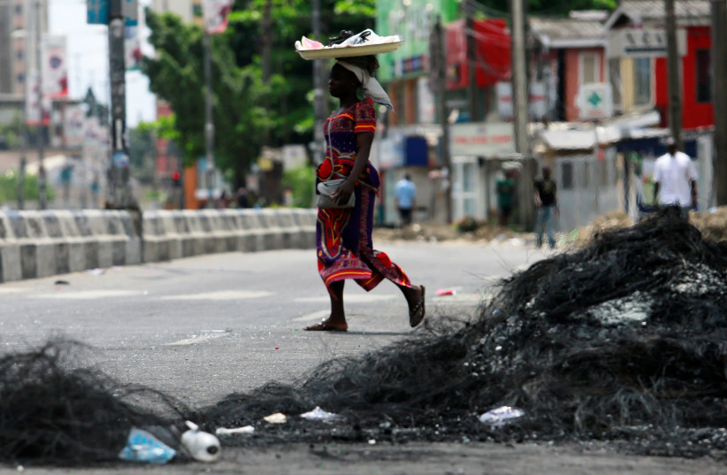 A woman walks past the remains of a burnt barricade in Surulere area of Lagos, Nigeria October 23, 2020.  (credit: REUTERS/AFOLABI SOTUNDE)