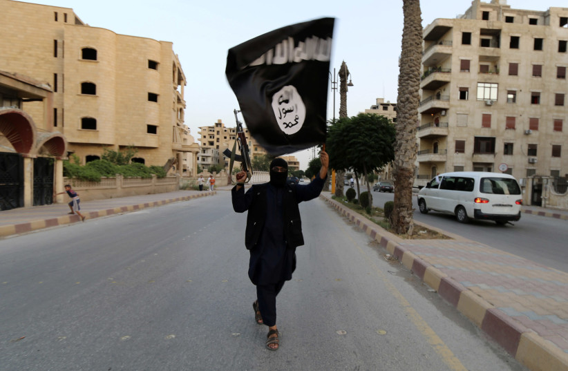 A member loyal to the Islamic State in Iraq and the Levant (ISIL) waves an ISIL flag in Raqqa June 29, 2014. The offshoot of al Qaeda which has captured swathes of territory in Iraq and Syria has declared itself an Islamic "Caliphate" and called on factions worldwide to pledge their allegiance, a st (photo credit: REUTERS/STRINGER)