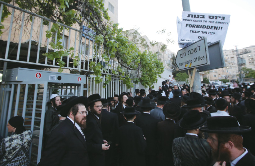 HUNDREDS OF haredi protesters gather outside the IDF recruitment office in Jerusalem’s Mekor Baruch neighborhood to protest IDF induction, in 2018.