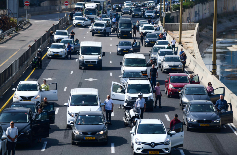 People stand still in Tel Aviv, as a two-minute siren is sounded across Israel to mark Holocaust Remembrance Day on April 8, 2021. (photo credit: TOMER NEUBERG/FLASH90)