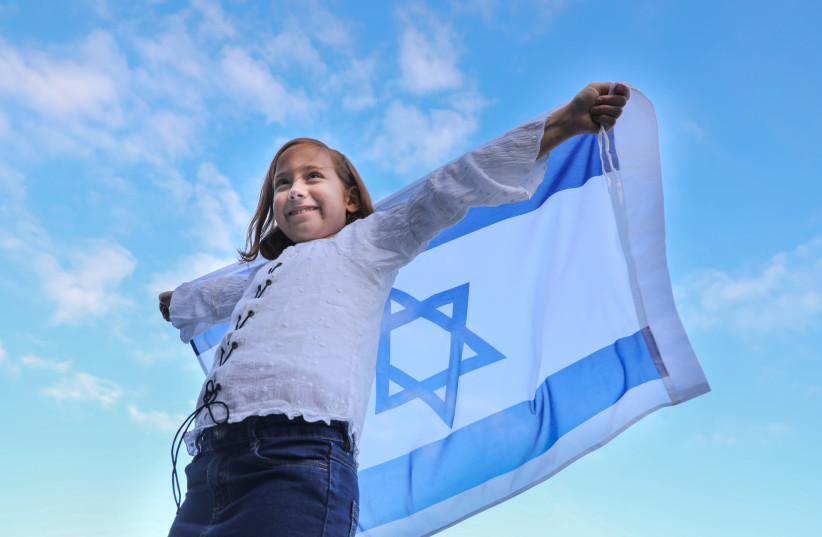 A young girl raises an Israeli flag.  (photo credit: MARC ISRAEL SELLEM)