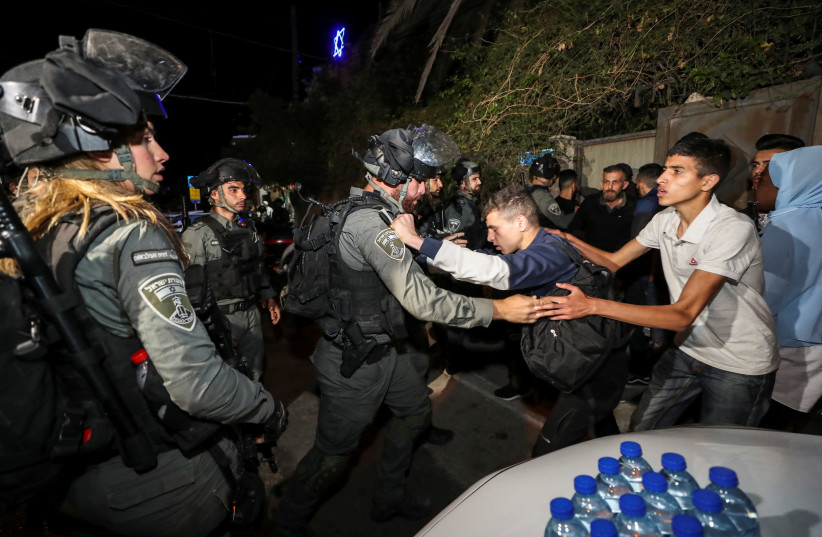An Israeli border policeman scuffles with a Palestinian protester during clashes amid ongoing tension ahead of an upcoming court hearing in an Israeli-Palestinian land-ownership dispute in the Sheikh Jarrah neighbourhood of East Jerusalem May 3, 2021. (photo credit: REUTERS/AMMAR AWAD)