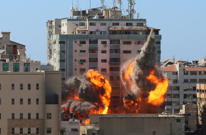 An explosion is seen near a tower housing AP, Al Jazeera offices during Israeli missile strikes in Gaza city, May 15, 2021. (credit: ASHRAF ABU AMRAH / REUTERS)