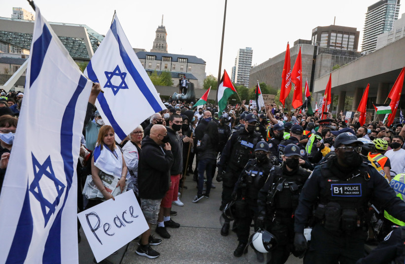 Police officers stand in line to separate protesters supporting Palestine from a small group of Israel supporters in front of city hall in Toronto, Ontario, Canada May 15, 2021. (credit: CHRIS HELGREN/REUTERS)