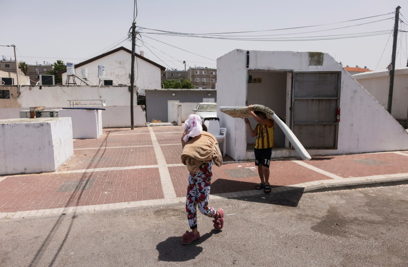 Israeli kids carry their sleeping items as they walk out of a bomb shelter following Israel-Hamas truce, in Ashkelon, Israel May 21, 2021. (credit: RONEN ZVULUN/REUTERS)