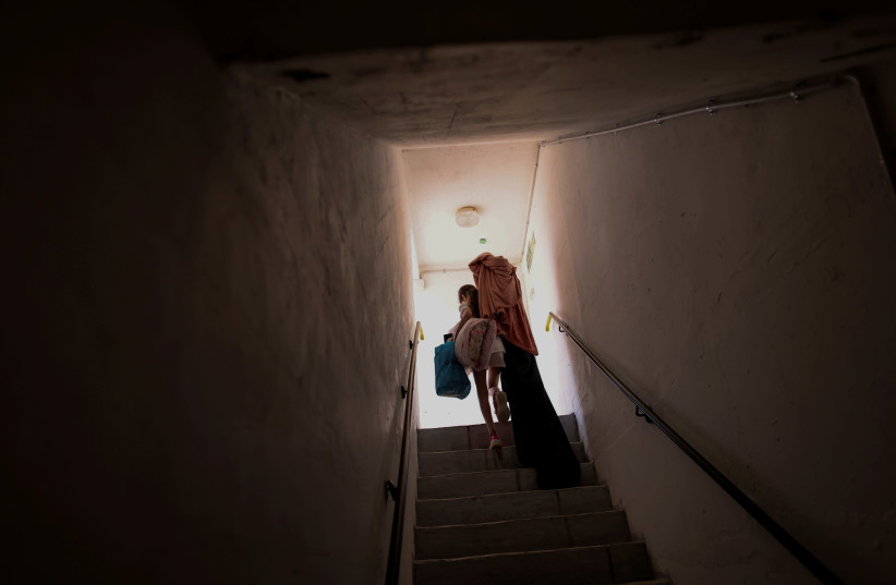 An Israeli girl carries her belongings as she walks out from a public bomb shelter back home, following Israel-Hamas truce, in Ashkelon, Israel May 21, 2021. (credit: RONEN ZVULUN/REUTERS)