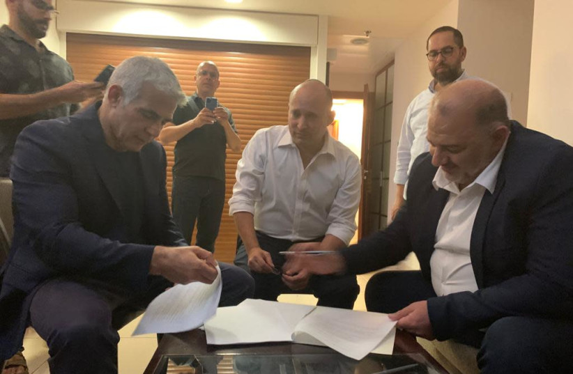 Naftali Bennett, Yair Lapid and Mansour Abbas are seen signing a coalition deal. (photo credit: RA'AM)