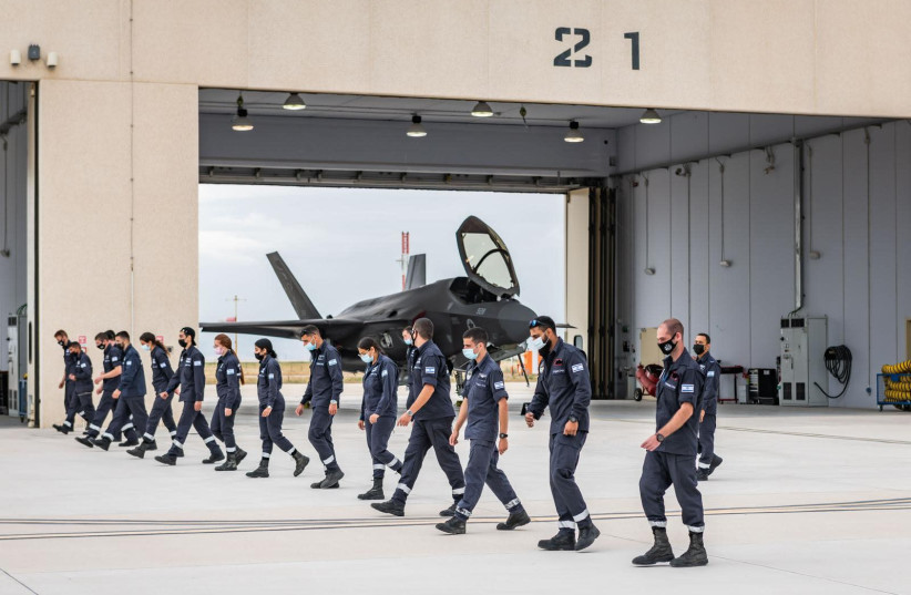 Israeli Air Force (IAF) personnel are seen marching by a fighter jet hanger. (credit: IDF SPOKESPERSON'S UNIT)