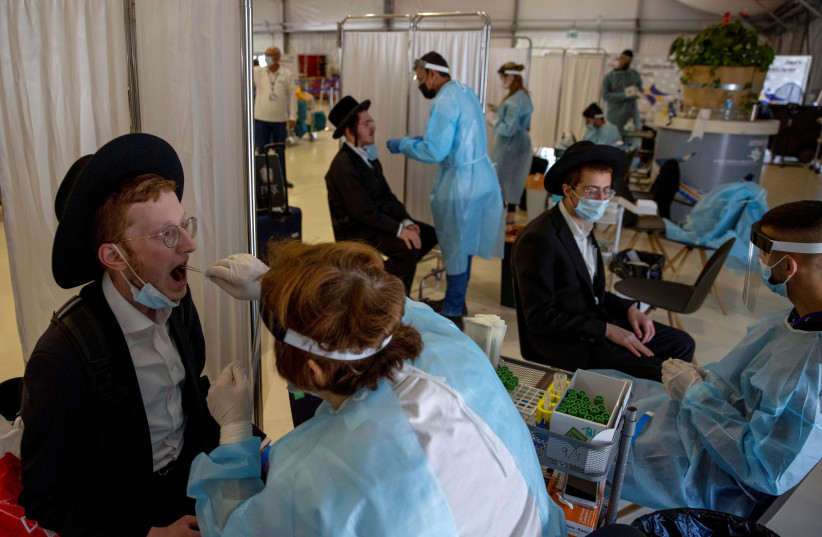 Healthcare workers take swab samples from ultra-Orthodox passengers returning from abroad at Ben-Gurion Airport on April 13 (credit: RONEN ZVULUN/REUTERS)