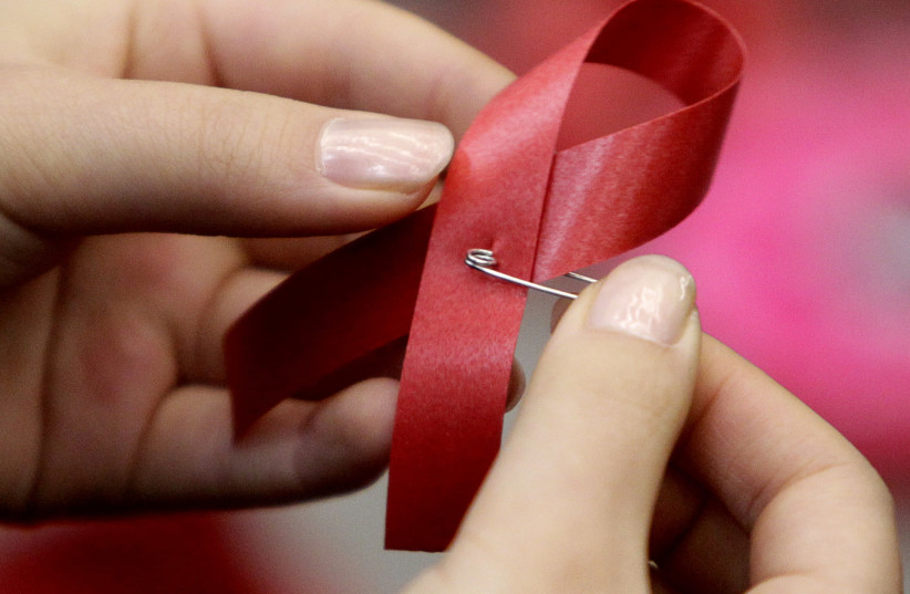 A student makes an AIDS red ribbon during a World AIDS Day event in Beijing, December 1, 2010 (credit: JASON LEE / REUTERS)