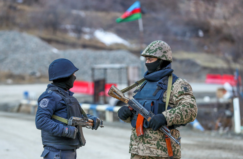  An Azeri soldier and police officer talk as they stand guard at the Kalbajar district, Azerbaijan, December 21, 2020 (photo credit: AZIZ KARIMOV/REUTERS)