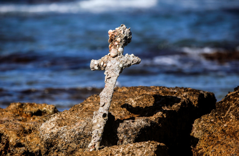  A sword believed to have belonged to a Crusader who sailed to the Holy Land almost a millennium ago stands in the water near to where it was recovered from the Mediterranean seabed by an amateur diver, the Israel Antiquities Authority said, Caesarea, Israel October 18, 2021 (credit: RONEN ZVULUN/REUTERS)
