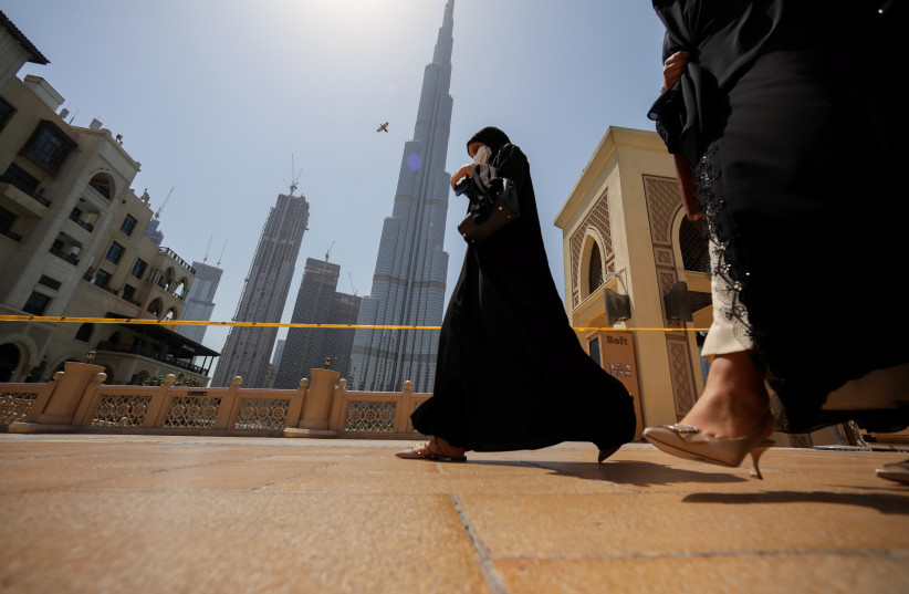  Women walk past the Burj Khalifa in Dubai, United Arab Emirates, June 11, 2021 (credit: REUTERS/CHRISTOPHER PIKE)