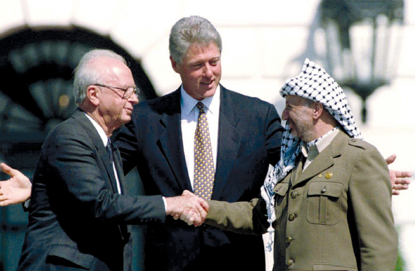  PRIME MINISTER Yitzhak Rabin shakes hands with PLO chairman Yasser Arafat, as US president Bill Clinton looks on at the White House at the signing of the Oslo I Declaration of Principles on September 13, 1993. (credit: GARY HERSHORN/REUTERS)