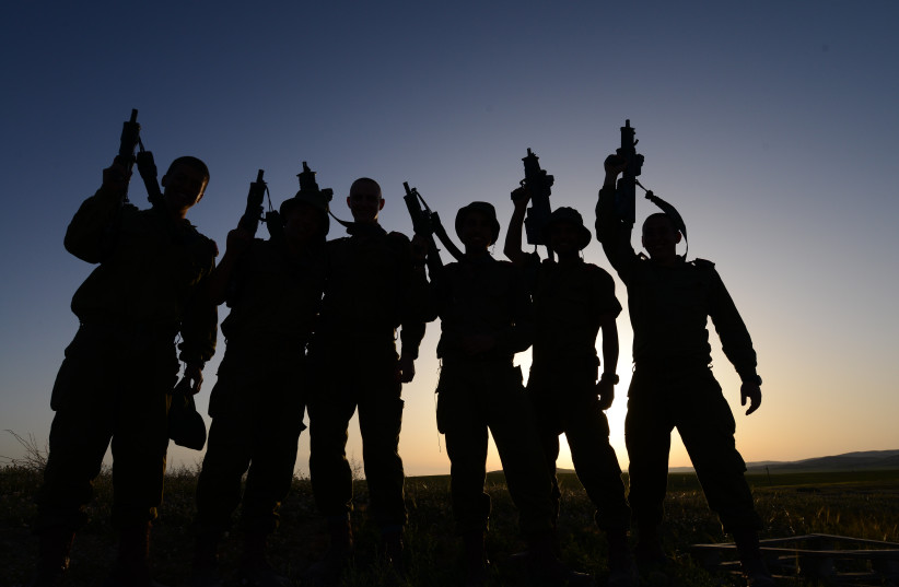 IDF soldiers of the ultra-Orthodox 'Nahal Brigade' seen silhouetted holding their weapons at an Israeli army base in Beersheba, southern Israel, March 31, 2014. (credit: MENDY HECHTMAN/FLASH90)