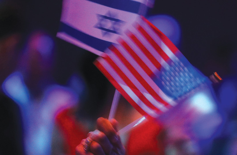 AN AUDIENCE MEMBER waves Israeli and American flags at the Israeli-American Council National Summit in Hollywood, Florida.