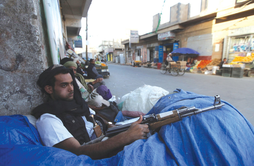  A HOUTHI fighter sits behind sandbags near a checkpoint in Sanaa, Yemen. (photo credit: MOHAMED AL-SAYAGHI/REUTERS)