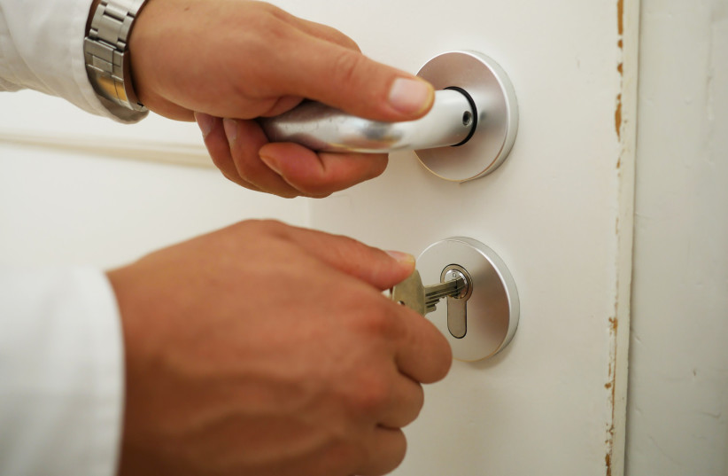  A person's hands unlock a door, one hand on the doorknob (Illustrative) (credit: PIXABAY)