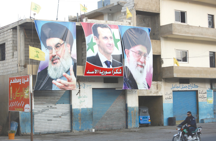  POSTERS DEPICT the Hezbollah, Syrian and Iranian leaders near the Lebanese-Syrian border. How can we ignore that Russia allows attacks against targets of Iran and its proxies in Syria? (photo credit: AZIZ TAHER/REUTERS)