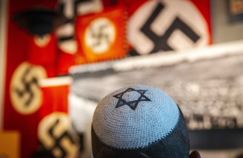  Visitors seen standing next to a display of swastika banners at the Yad Vashem Holocaust Memorial museum in Jerusalem on April 26, 2022, ahead of Israeli Holocaust Remembrance Day.  (photo credit: OLIVIER FITOUSSI/FLASH90)