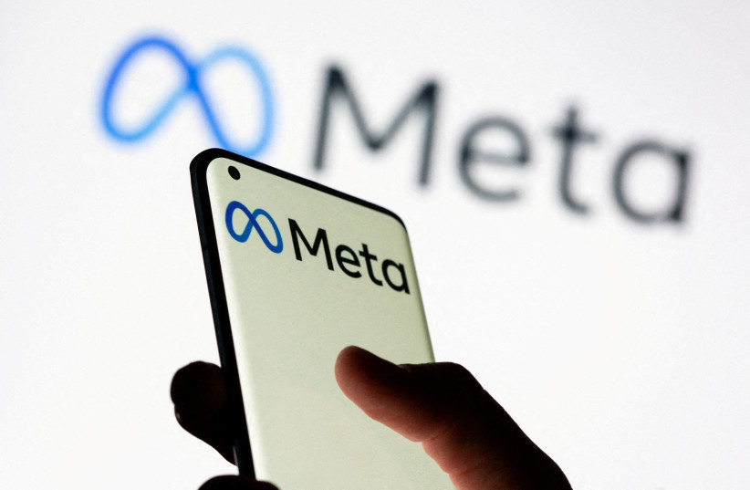  Woman holds smartphone with Meta logo in front of a displayed Facebook's new rebrand logo Meta in this illustration picture taken October 28, 2021.  (credit: REUTERS/DADO RUVIC/ILLUSTRATION)
