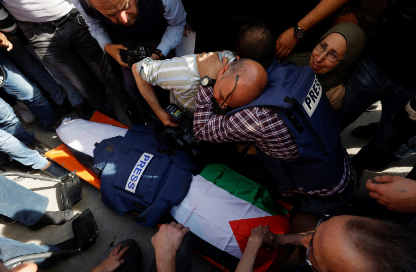 Journalists mourn next to the body of Al Jazeera reporter Shireen Abu Akleh, who was killed during IDF-Palestinian clashes in Jenin on May 11, 2022. (photo credit: REUTERS/MOHAMAD TOROKMAN)