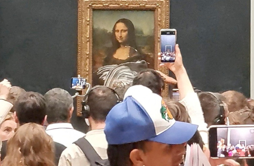 Visitors take pictures and video of the painting ''Mona Lisa'' after cake was smeared on the protective glass at the Lourve Museum in Paris, France May 29, 2022 in this screen grab obtained from a social media video.