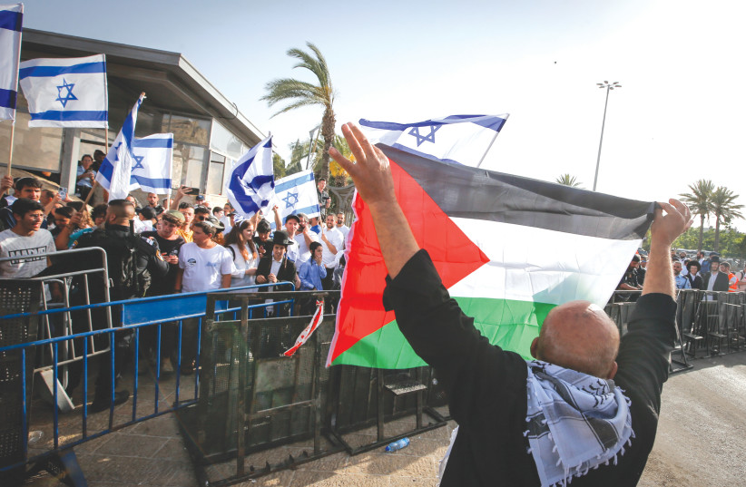  A MAN displays a Palestinian flag across from celebrants holding Israeli flags in Jerusalem’s Old City during Jerusalem Day festivities, last week. (credit: JAMAL AWAD/FLASH90)