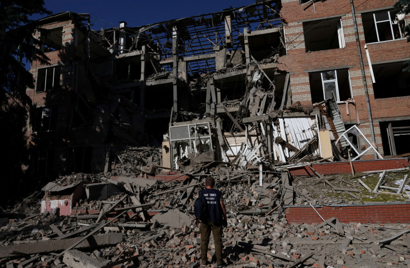  A worker from the war crimes prosecutor's office takes in the damage from overnight shelling that landed on a building of Kharkiv's Housing and Communal College as Russia's attack on Ukraine continues in Kharkiv, Ukraine, June 21, 2022.  (photo credit: Leah Mills/Reuters)