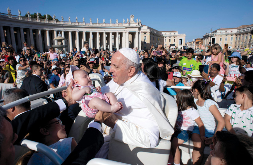  Pope Francis holds a child as he attends a mass in St. Peter’s Square on June 25.  (credit: VATICAN MEDIA/REUTERS)
