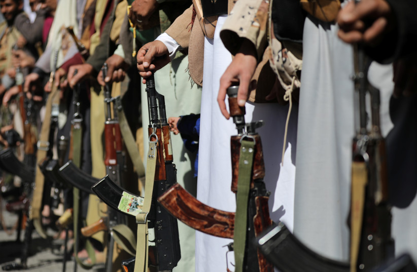 Houthi supporters hold their weapons during a demonstration outside the US embassy against the United States over its decision to designate the Houthis a foreign terrorist organisation, in Sanaa, Yemen January 18, 2021. (photo credit: REUTERS/KHALED ABDULLAH)