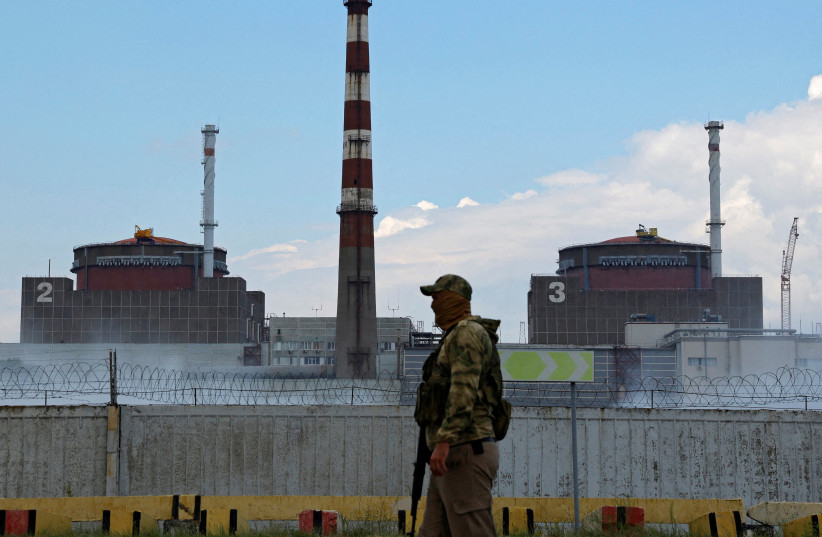A serviceman with a Russian flag on his uniform stands guard near the Zaporizhzhia Nuclear Power Plant in the course of Ukraine-Russia conflict outside the Russian-controlled city of Enerhodar in the Zaporizhzhia region, Ukraine August 4, 2022. (photo credit: REUTERS/Alexander Ermochenko/File Photo)