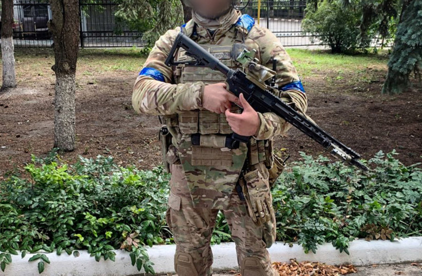 A Ukrainian service member stands on a Russian national flag, amid Russia's attack on Ukraine, in unknown location in Eastern Ukraine, in this handout picture released September 10, 2022.