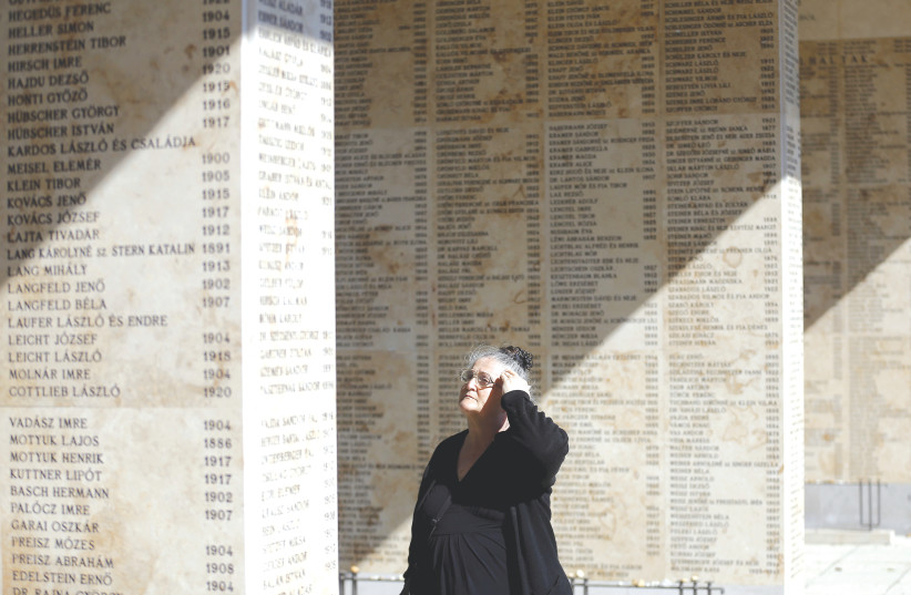  A WOMAN stands next to walls etched with the names of Holocaust victims, during a funeral for the remains of victims in the Jewish cemetery in Budapest, 2016 (photo credit: LASZLO BALOGH/REUTERS)