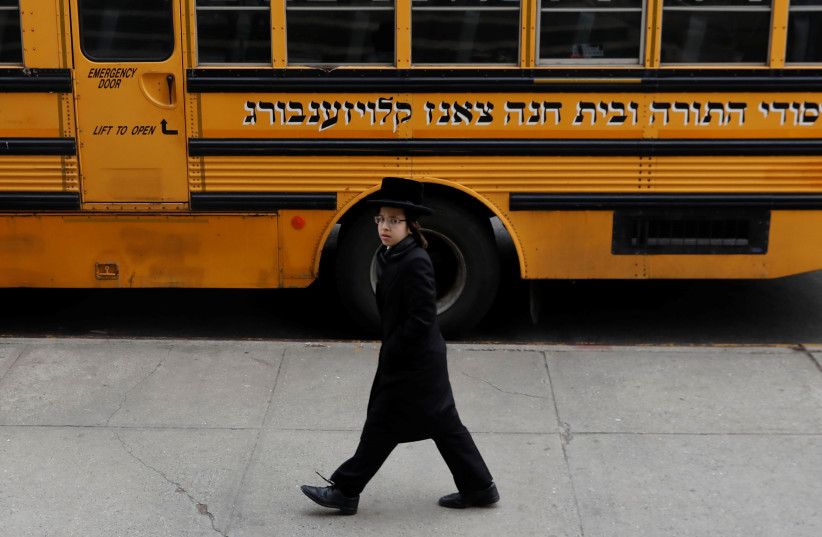  An Orthodox Jewish boy walks by a Yeshiva school bus, as New York City, April 9, 2019. (photo credit: REUTERS/SHANNON STAPLETON)