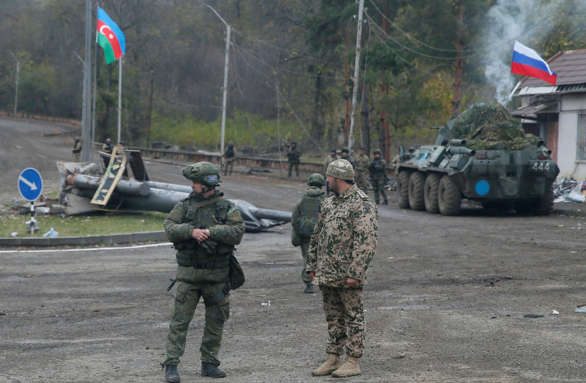  An Azerbaijani service member and a Russian peacekeeper stand guard at a checkpoint on the outskirts of Shusha (Shushi) in the region of Nagorno-Karabakh, November 13, 2020. (credit: STRINGER/ REUTERS)