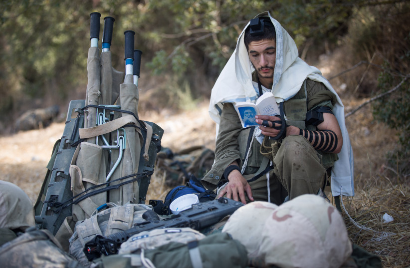  THE ZIONIST identity didn’t overcome the Jewish identity, nor did the opposite occur: An IDF soldier puts on tefillin. (credit: YONATAN SINDEL/FLASH90)