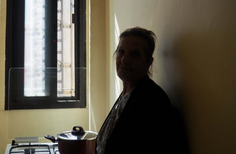 77岁的贝鲁特居民埃姆·拉菲(Em Rafi)在黑暗的厨房里加热洗澡水;她每天只能从国家公用事业公司得到几个小时的电力。(图片来源:THE MEDIA LINE)