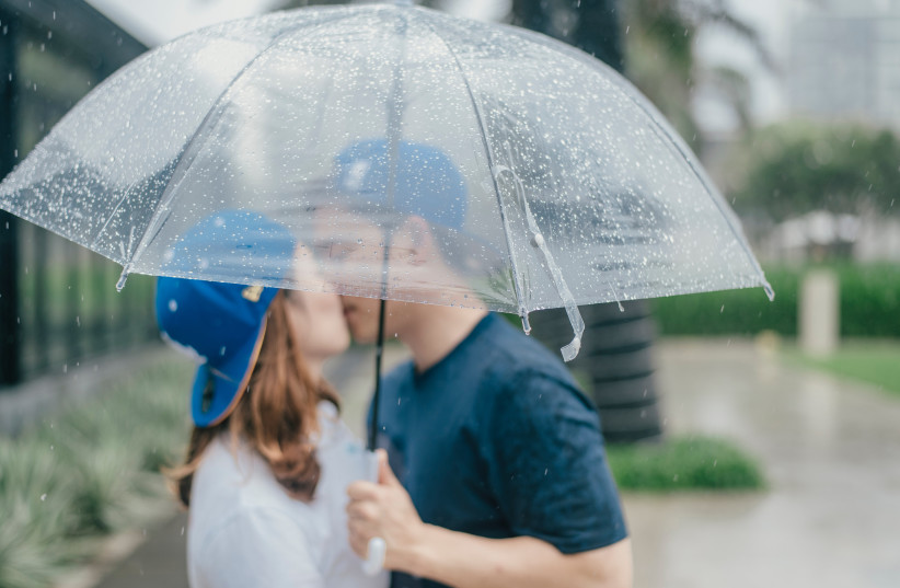  A couple kiss under an umbrella in the rain. (credit: PEXELS)