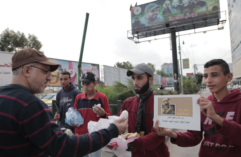 Palestinian supporters of the Islamic Jihad movement distribute sweets in celebration of the terror attack carried out by a Palestinian man earlier today in the West Bank, in Gaza City, on November 15, 2022. (credit: ATIA MOHAMMED/FLASH90)