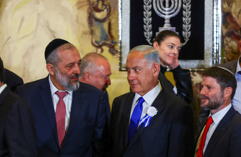  Benjamin Netanyahu looks at Shas leader MK Aryeh Deri as they stand with other members of the new Israeli parliament after their swearing-in ceremony in Jerusalem November 15, 2022.  (credit: RONEN ZVULUN/REUTERS)