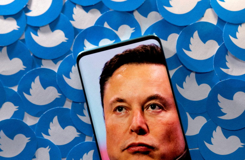  An image of Elon Musk is seen on a smartphone placed on printed Twitter logos in this picture illustration taken April 28, 2022.  (credit: REUTERS/DADO RUVIC/ILLUSTRATION/FILE PHOTO)