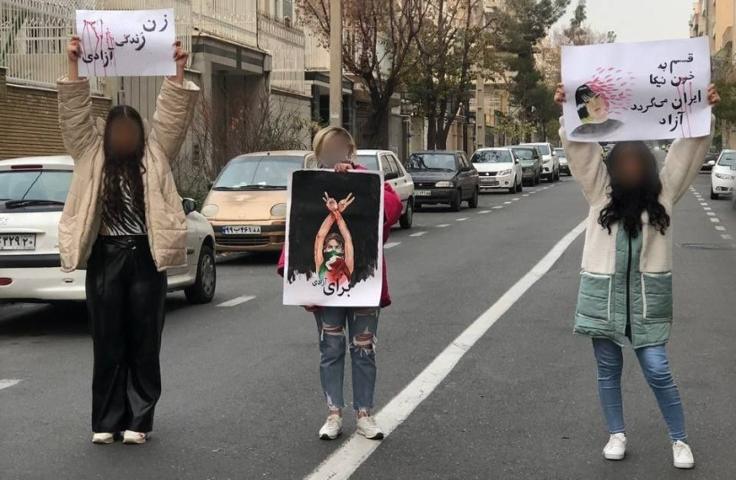  Iranians protest, holding signs with slogans such as ''women, life, freedom'' and'' ''I swear by the good blood of Iran it will be free.'' December 2022 (credit: 1500tasvir)