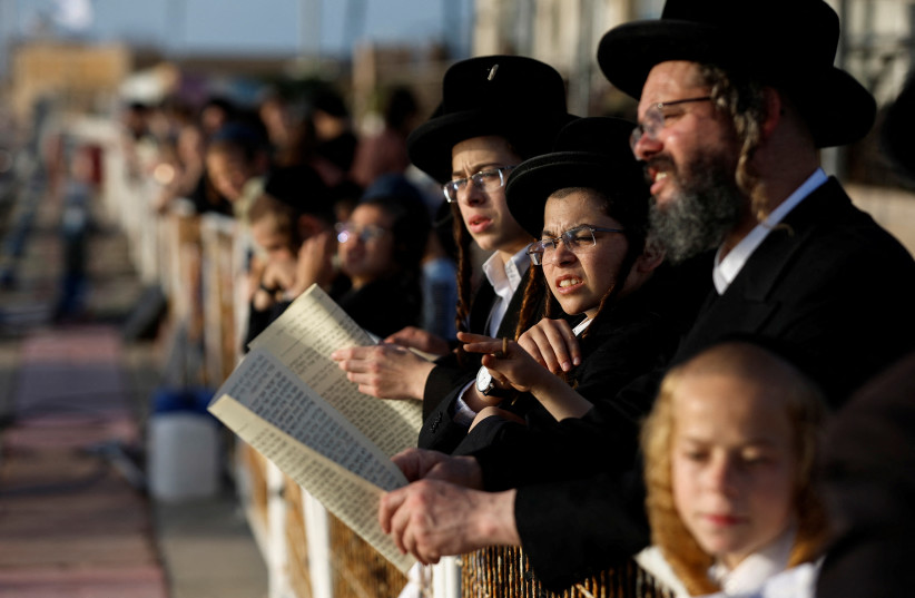 An ultra-Orthodox Jewish family takes part in the Tashlikh ritual, to symbolically cast away sins, ahead of Yom Kippur, the Jewish Day of Atonement, in Ashdod, Israel, October 3, 2022. (photo credit: REUTERS/AMIR COHEN)