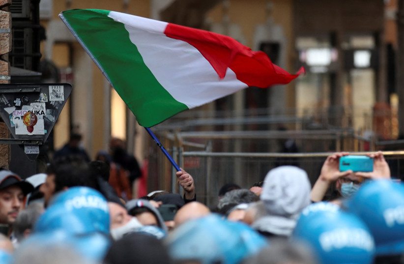  A demonstrator waves an Italian flag during a restaurant and small business owners' protest calling for their businesses to be allowed to re-open, despite no authorization for the demonstration by the government, amid the coronavirus disease (COVID-19) outbreak, in Rome, Italy, April 12, 2021. (credit: REUTERS/YARA NARDI)