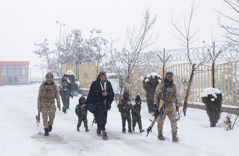  Taliban soldiers with their children dressed in military uniforms and holding plastic weapons, walk on a snow-covered street on a snowy day in Kabul, Afghanistan, January 29, 2023. (credit: ALI KHARA/REUTERS)