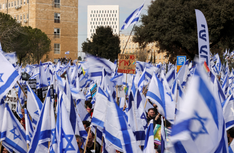  Israelis hold flags and posters as they demonstrate on the day Israel's constitution committee is set to start voting on changes that would give politicians more power on selecting judges while limiting Supreme Court's powers to strike down legislation. (photo credit: REUTERS/AMMAR AWAD)