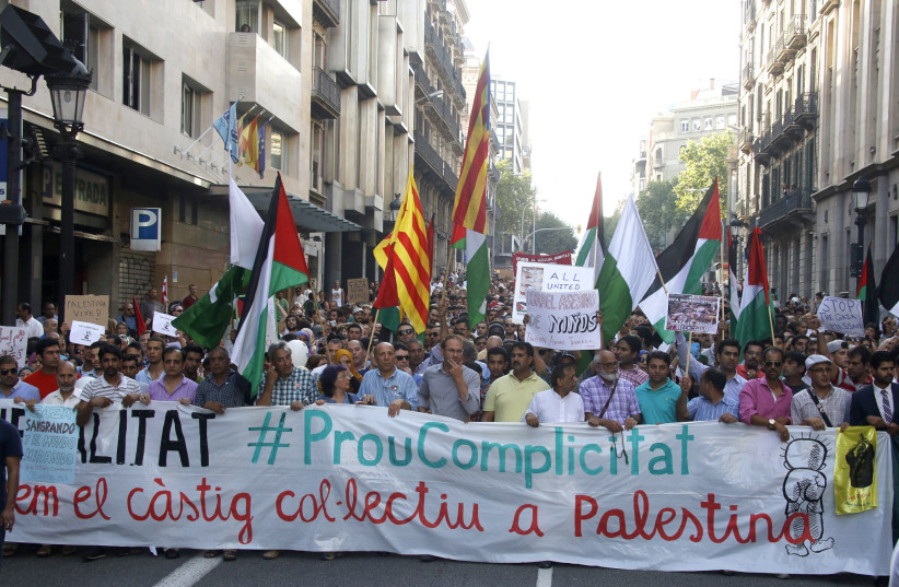  Demonstrators hold a banner during a protest in Barcelona, against Israel's military action in Gaza (photo credit: REUTERS/GUSTAU NACARINO)
